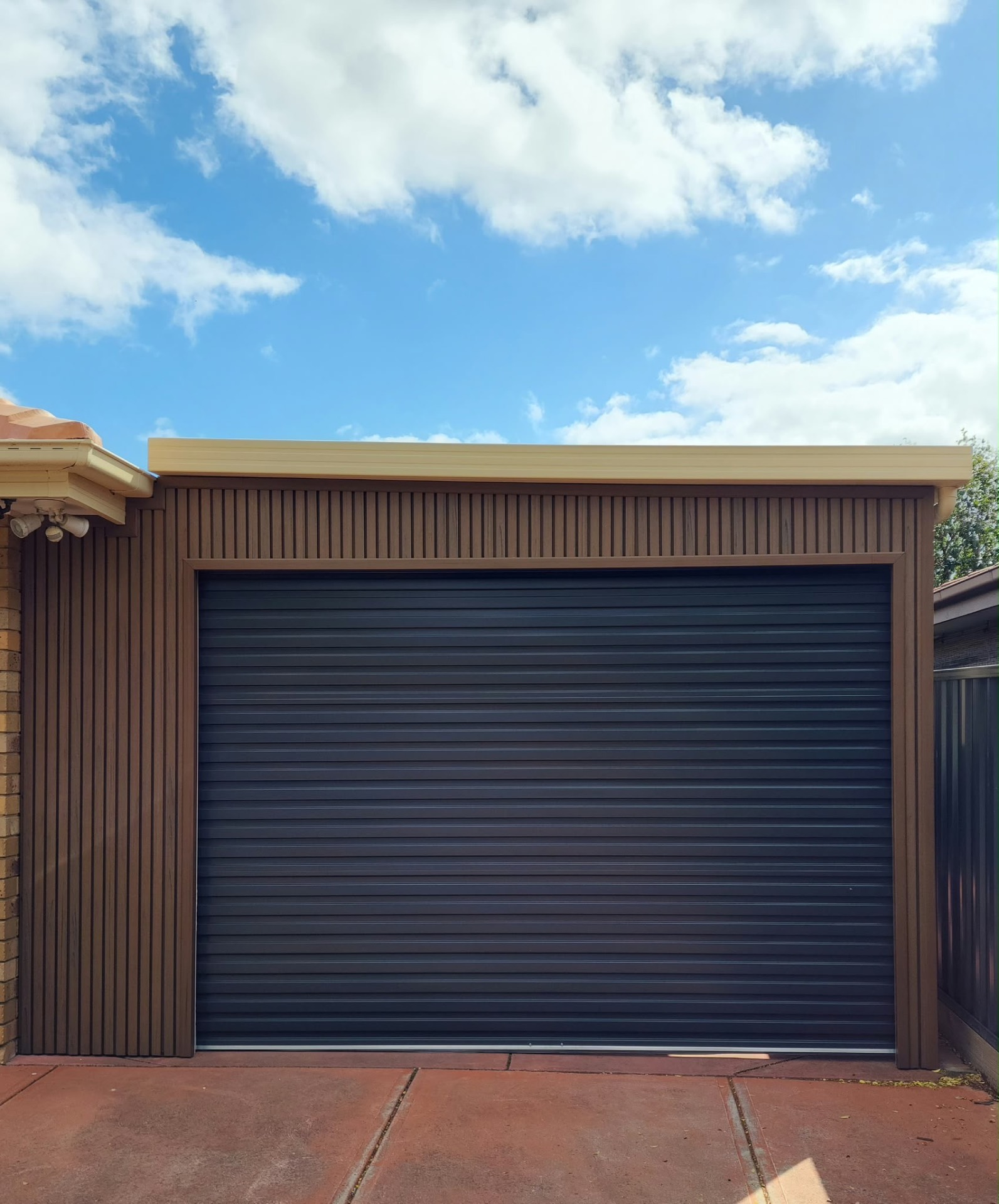 Dark sectional garage door with timber-look framing